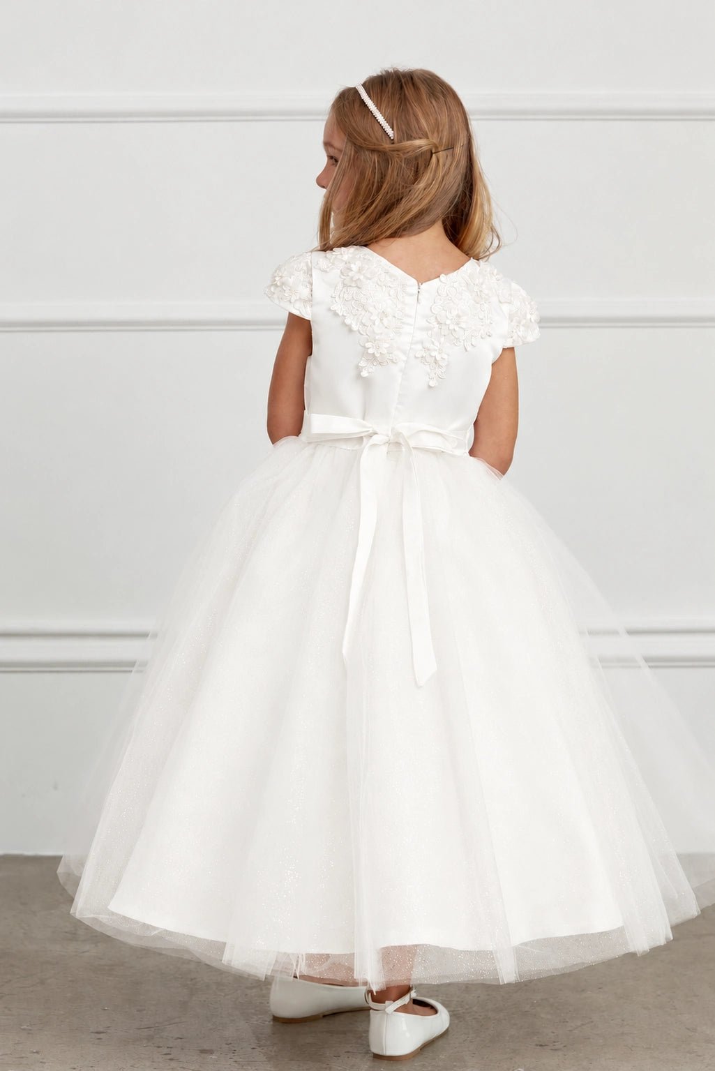 Emphasis on a satin back waist bow of the off-white flower girl dress.