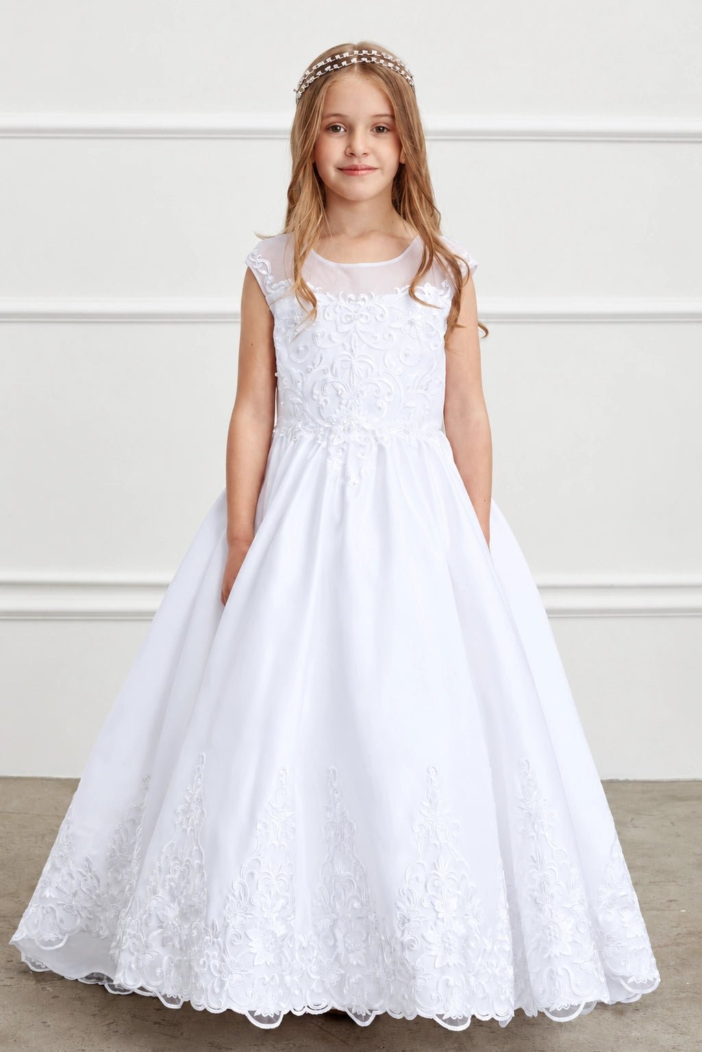 Lace cap sleeves extend from the white flower girl dress's sheer yoke.
