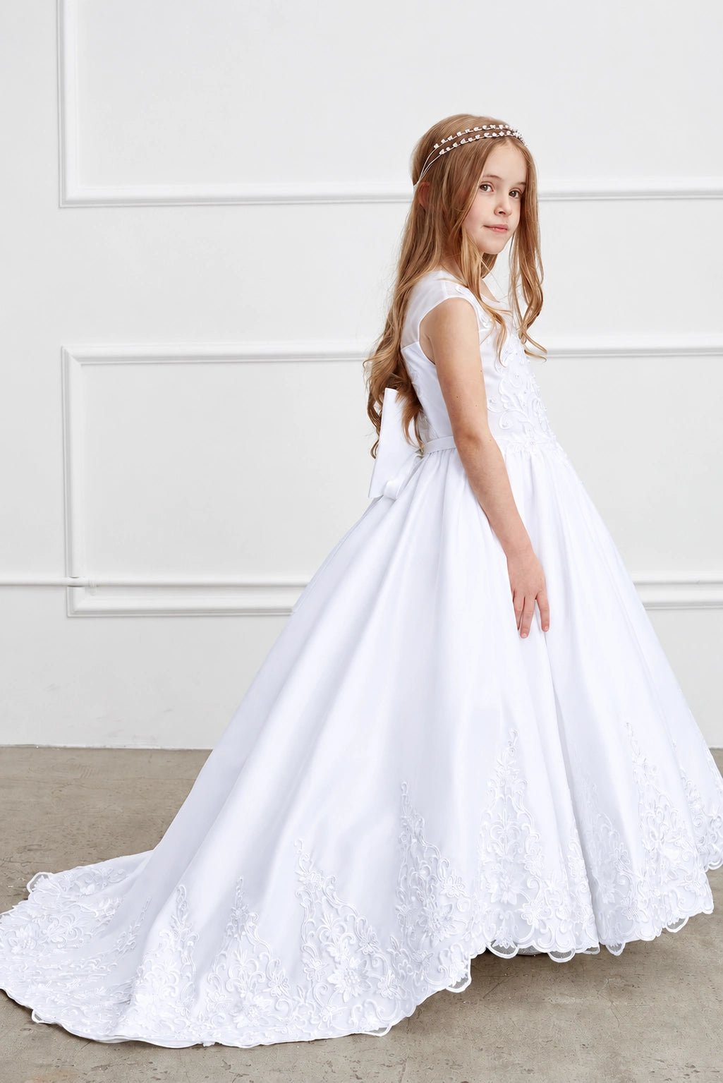 Wide floral lace follows the white flower girl dress's flowing hem.