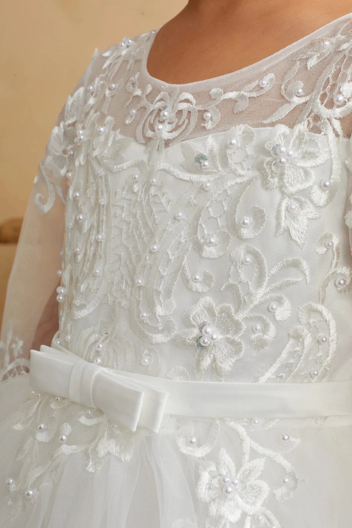 Close-up of the ivory illusion lace with sheer sleeves flower girl dress.