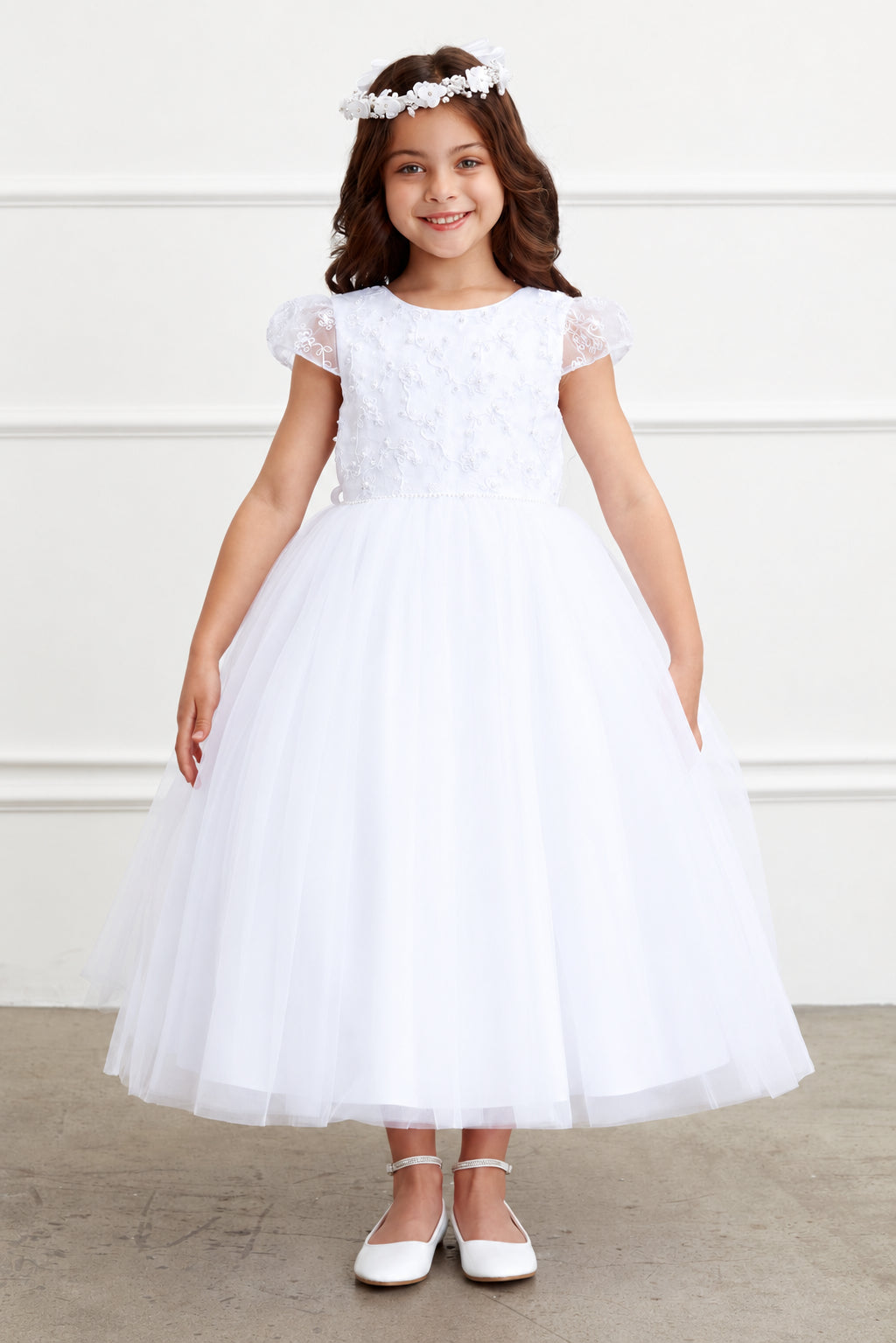 Fine tulle gathers into the white flower girl dress's full skirt.