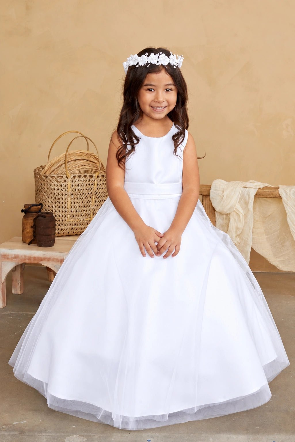 Smooth fabric curves into the white flower girl dress's round neckline.