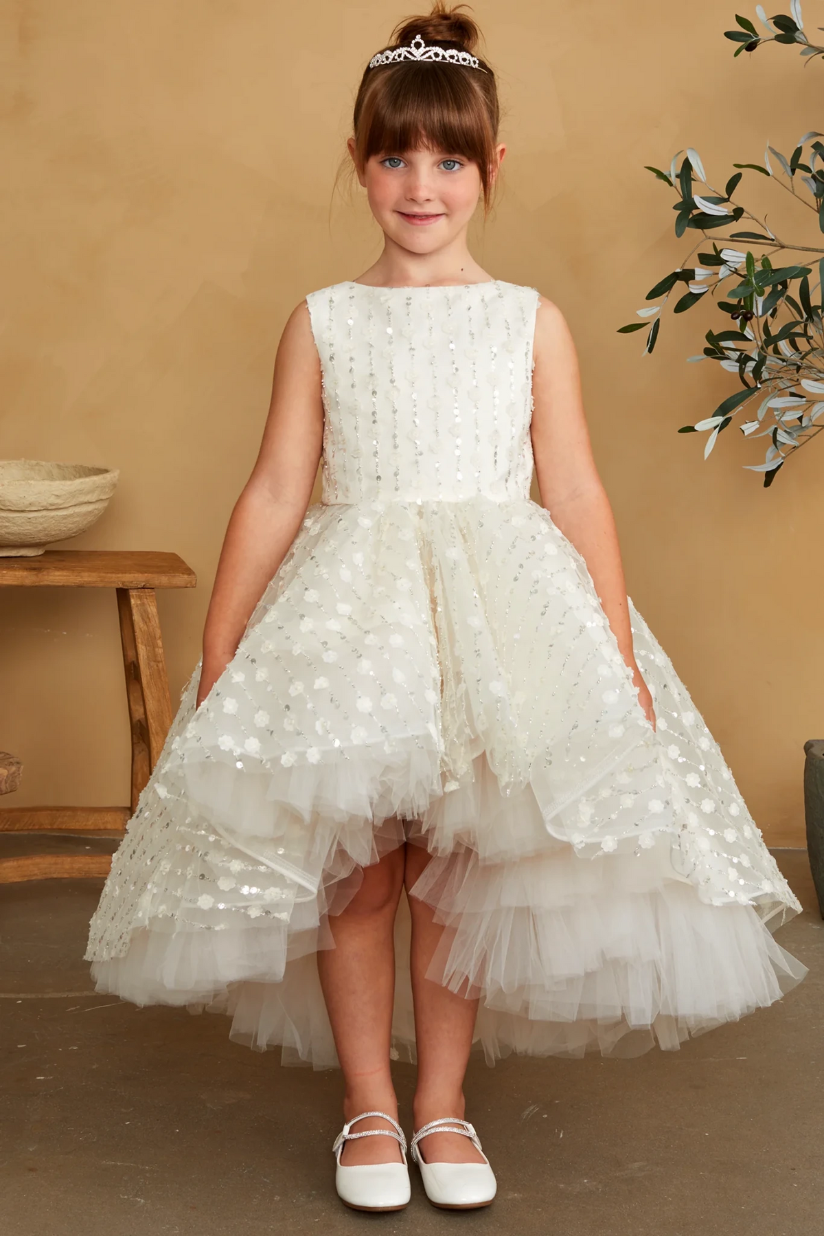 Dotted mesh tops the champagne flower girl dress's ruffled high-low hem.