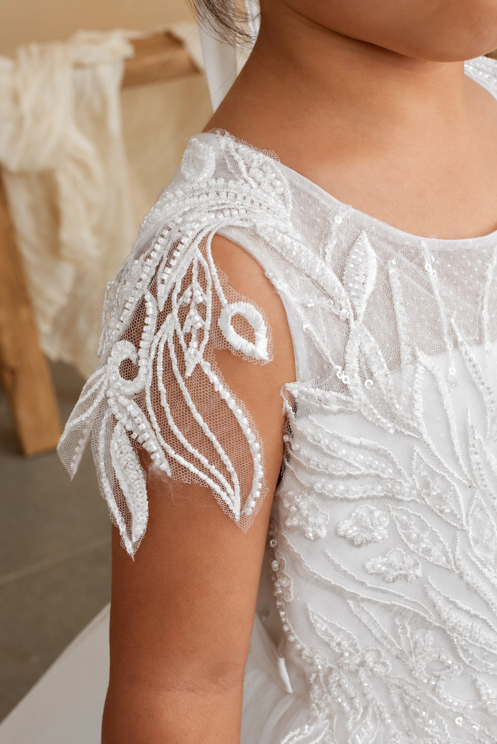 Off-White flower girl dress with a sheer leaf-shaped sleeve.
