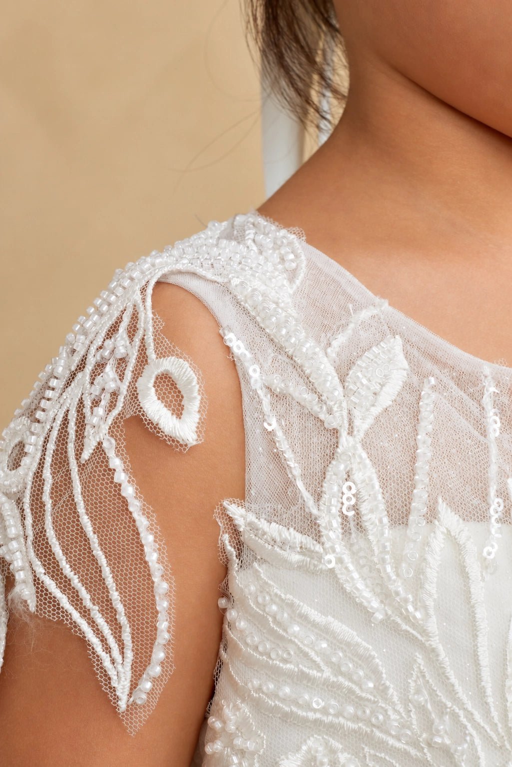 Pearl leaf embroidery accents this off-white flower girl dress.
