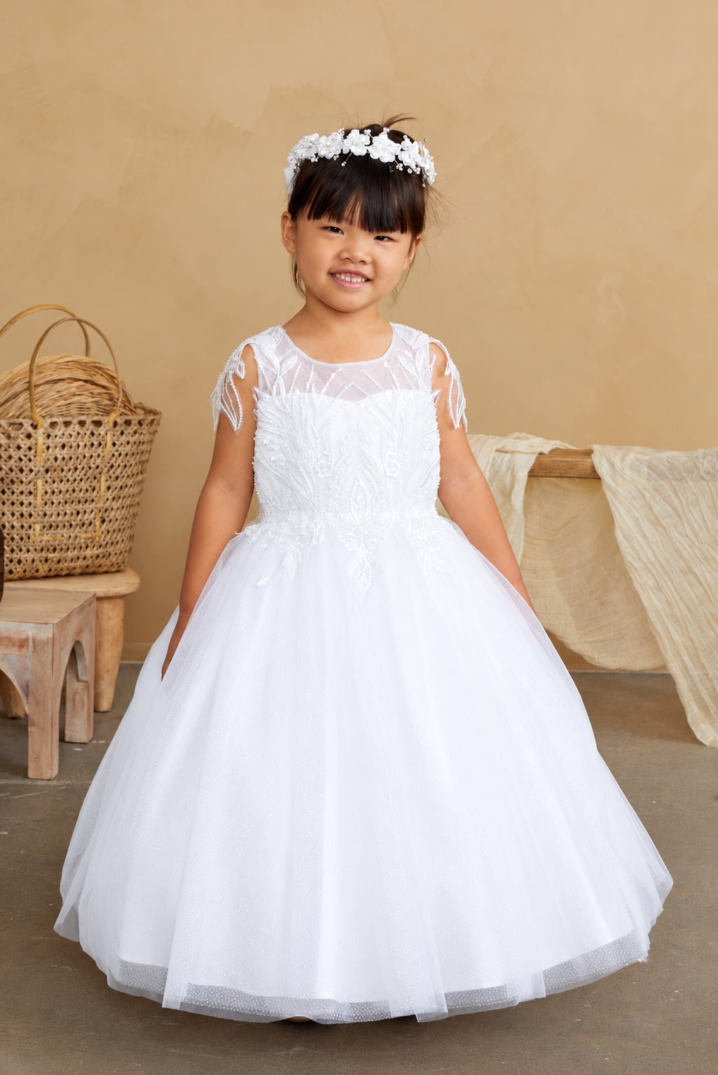 Pointed leaf embroidery overlays the white flower girl dress's sheer yoke.