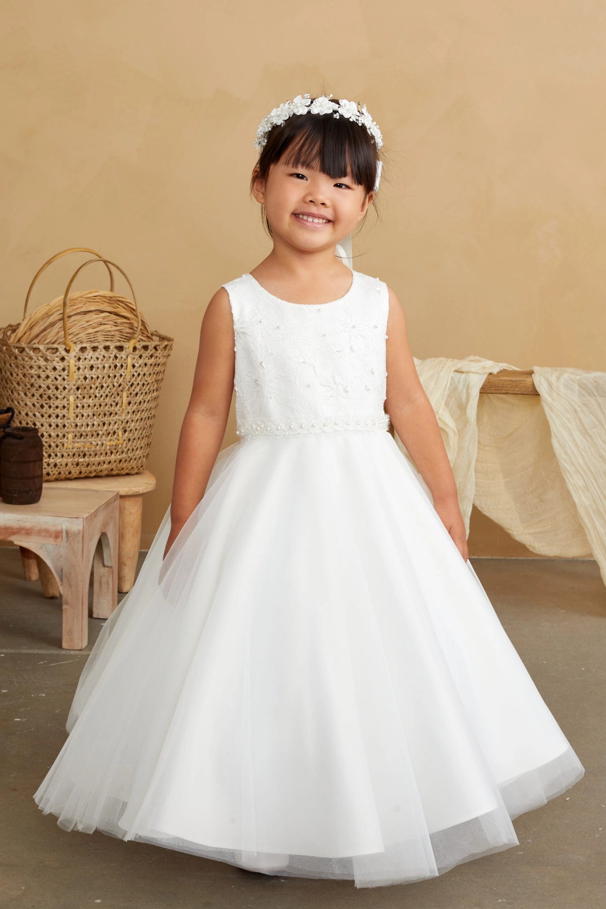 Scattered beads decorate the off-white flower girl dress's plain bodice.