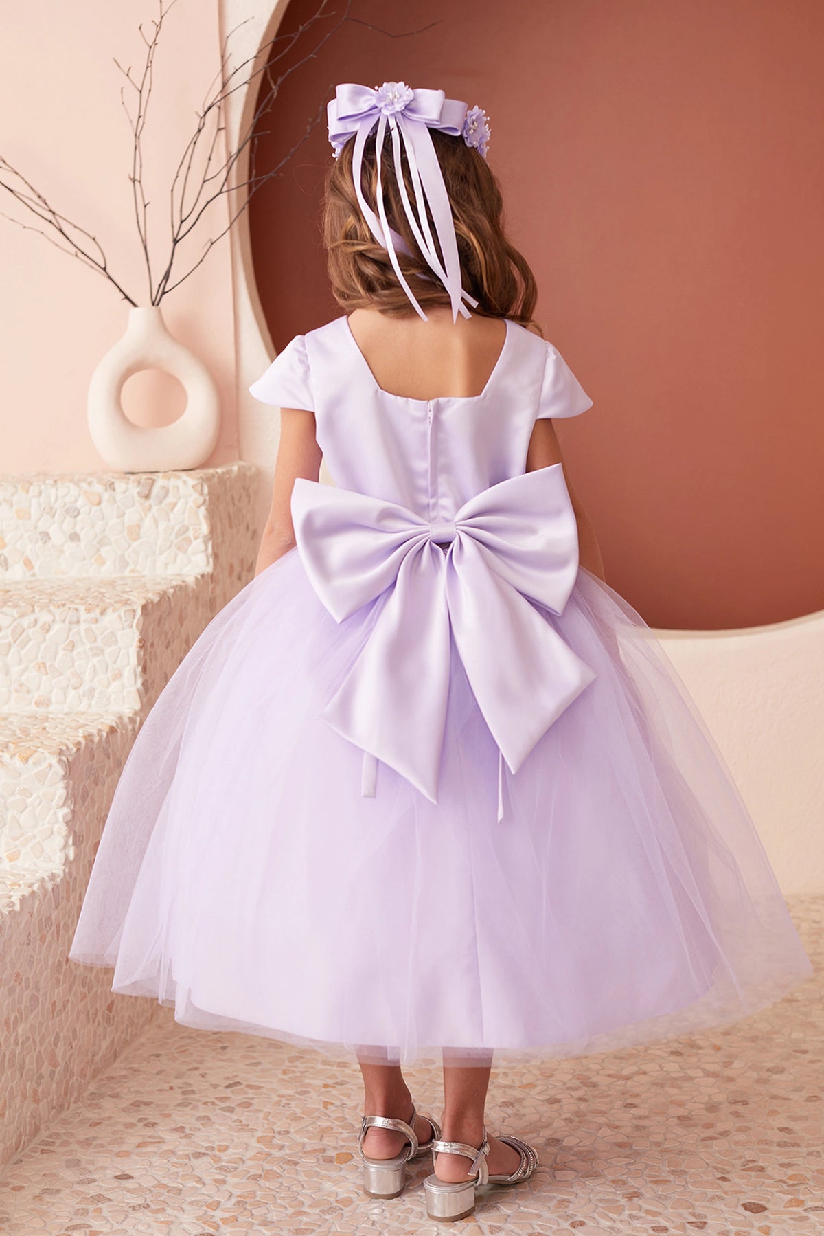 The Lilac kids pageant dress has a large satin bow and square back neckline.