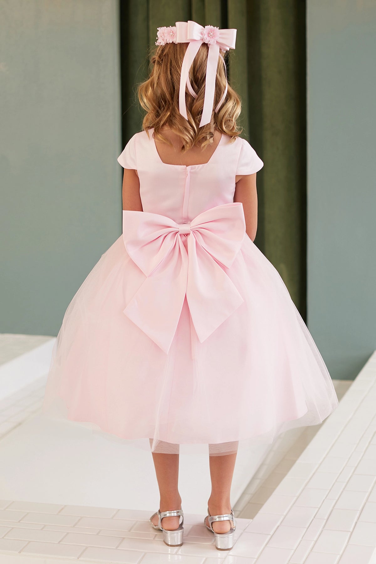 The Pink kids pageant dress has a large satin bow and square back neckline.