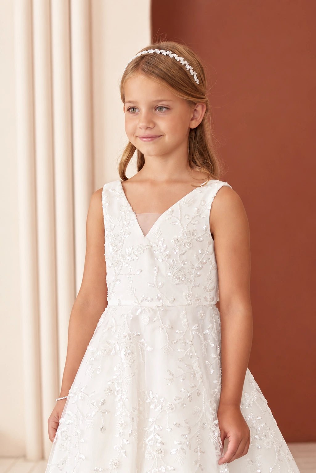 A view of an embroidered V neckline on the off-white flower girl dress.