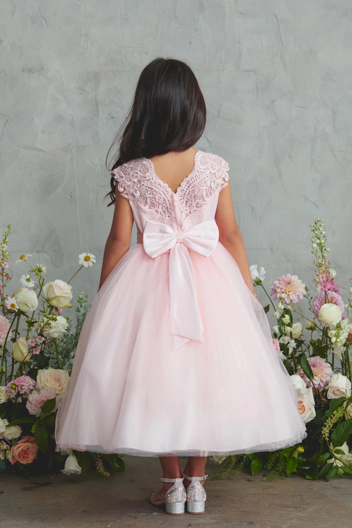 Large satin back bow shown on the blush flower girl dress.