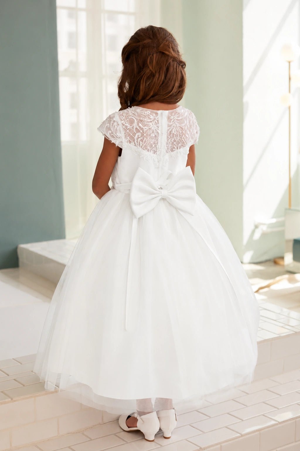 Looped satin creates the off-white flower girl dress's broad back bow.