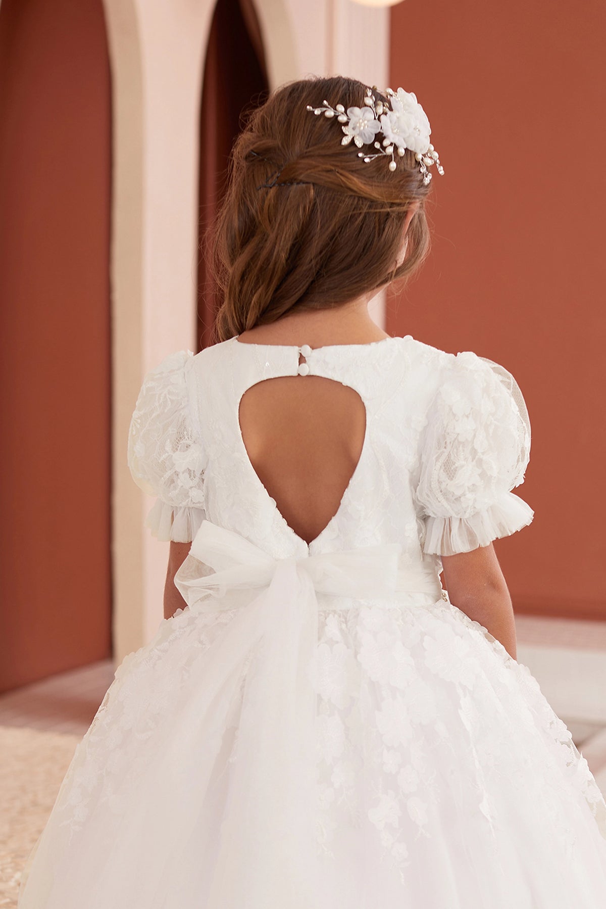 Heart-shaped opening in the off-white flower girl dress's back bodice.