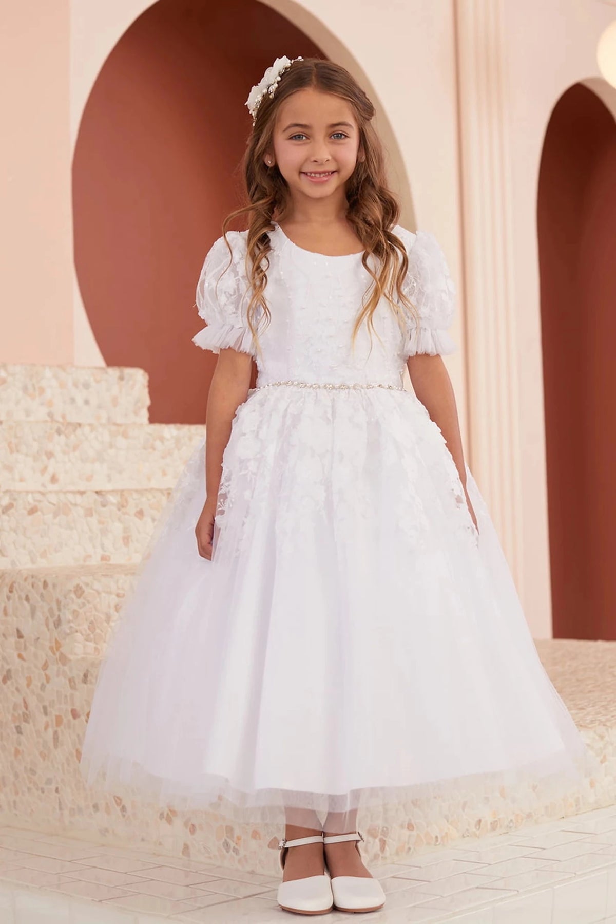 This white flower girl dress displays a pleated waist skirt.