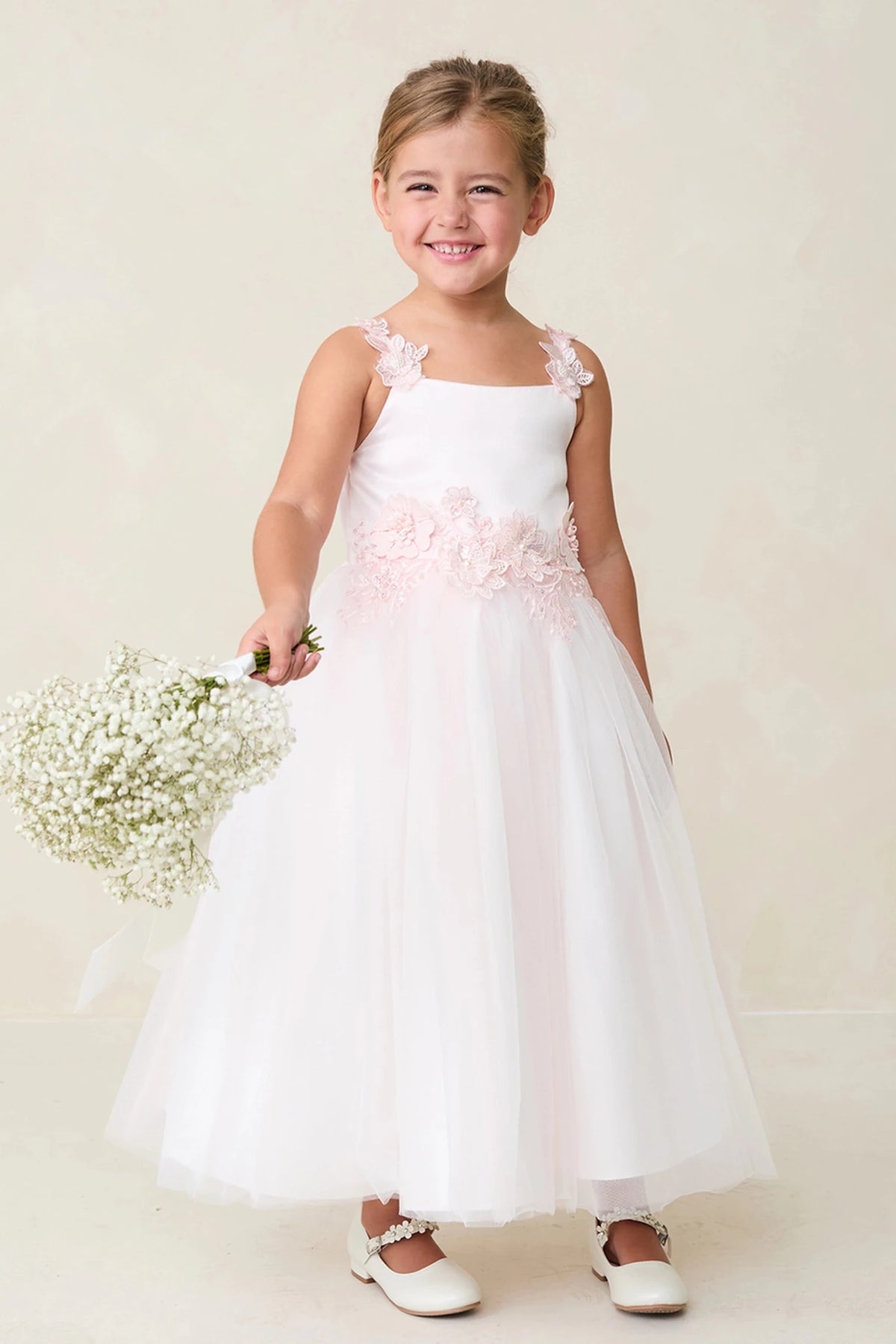 Blush flower girl dress featuring a flower-trimmed waist.