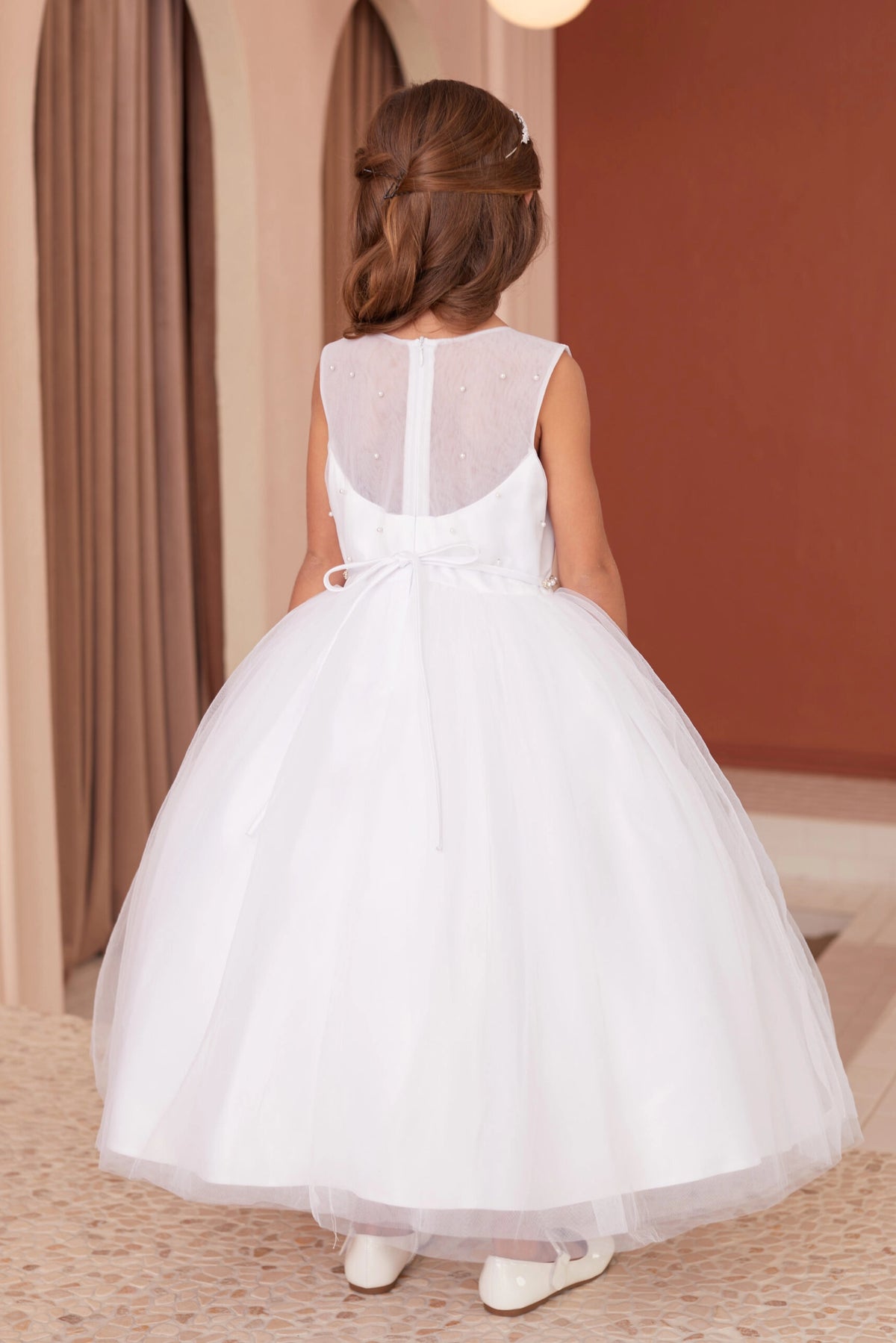 Detailed with sheer pearl back, this white flower girl dress.