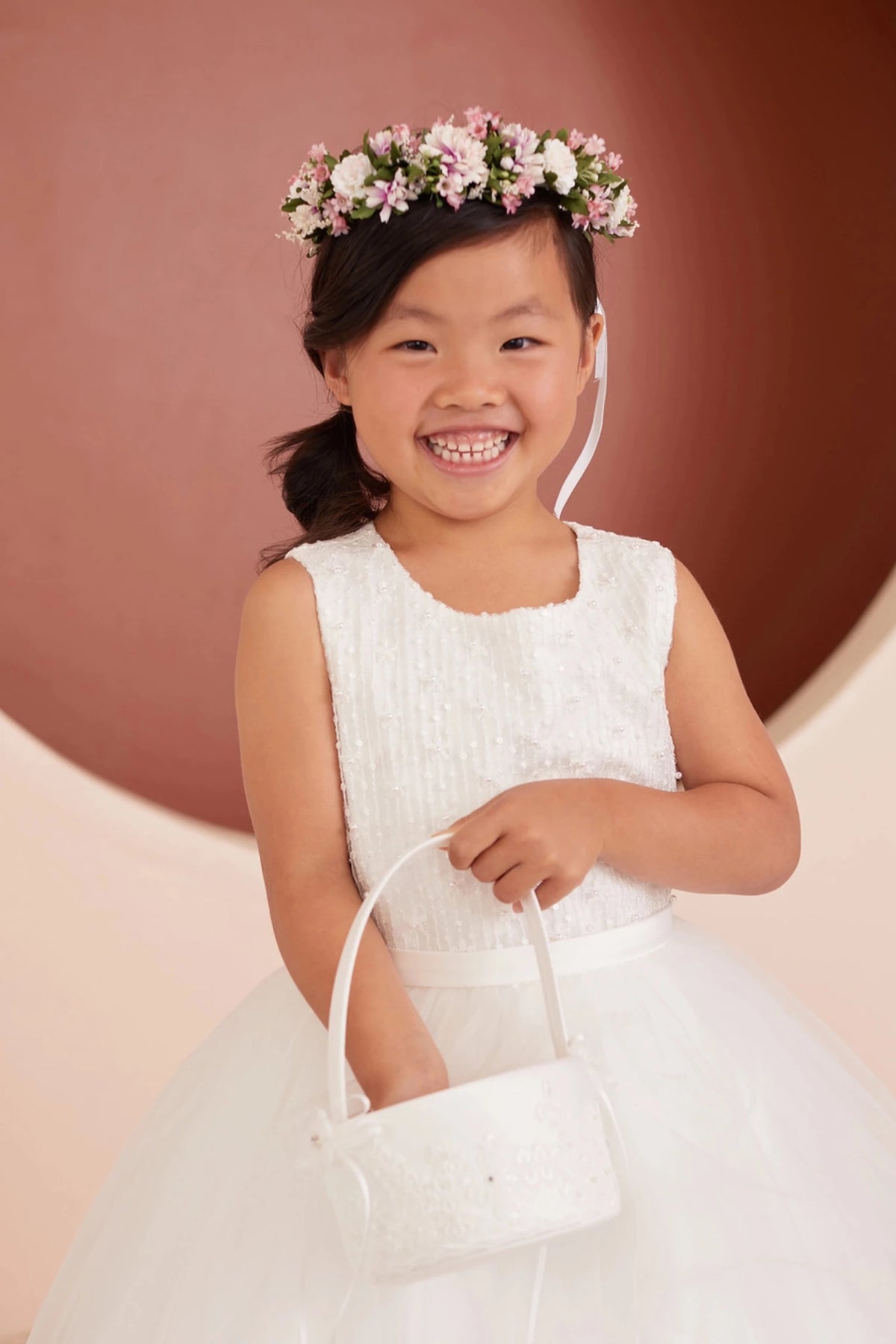 Vertical rows of tiny loops cover the off-white flower girl dress's bodice.