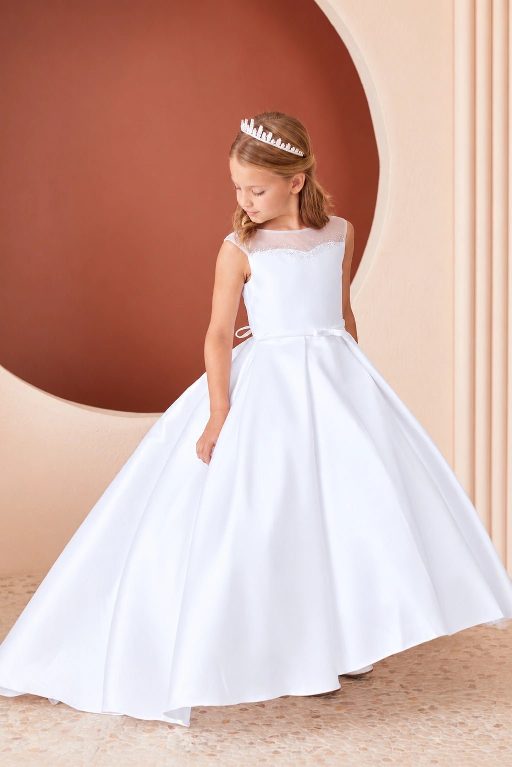 Fanning satin folds spread below the white flower girl dress's waist.