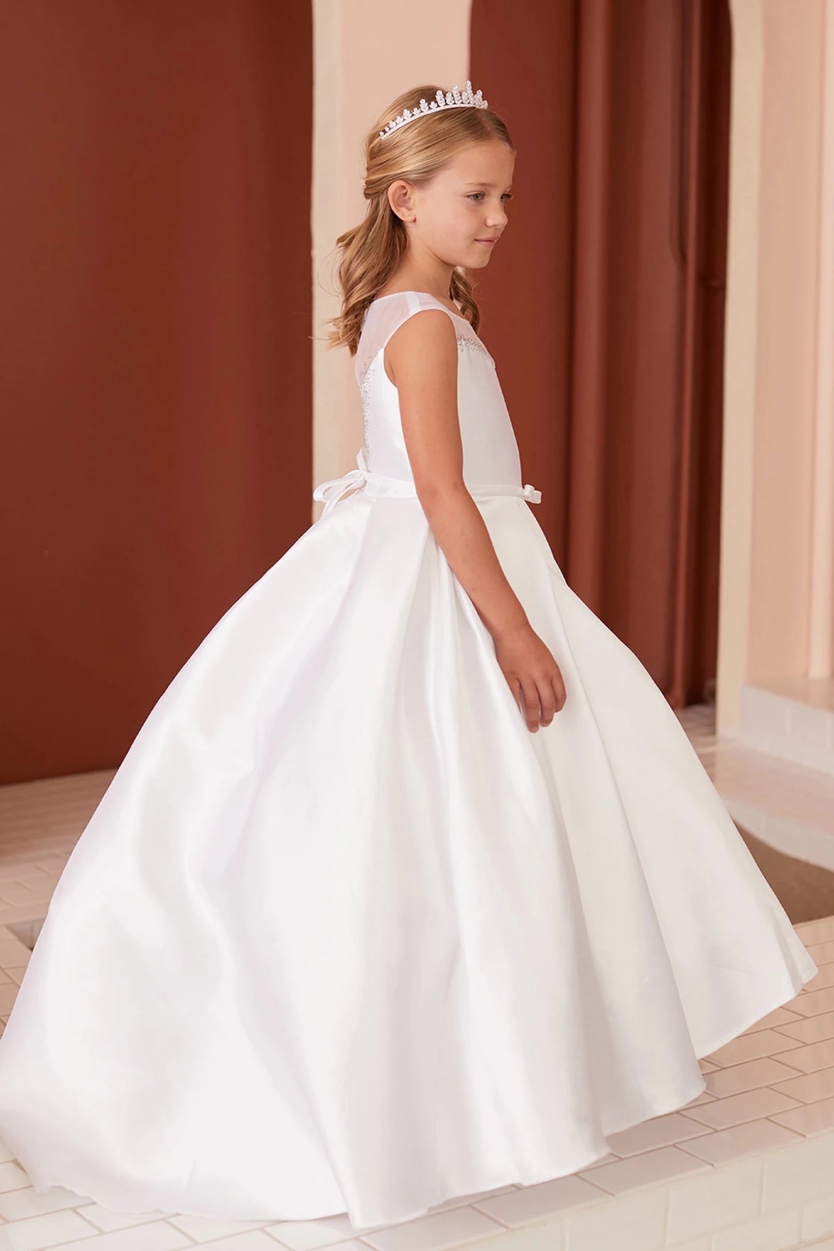 A view of a smooth satin hem on the white flower girl dress.