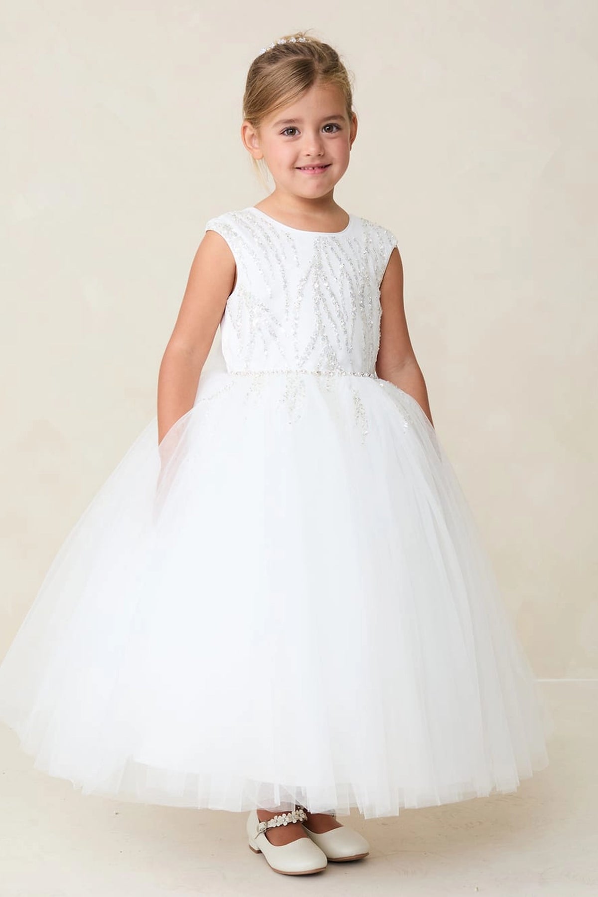 Beaded strands run vertically down the off-white flower girl dress's bodice.