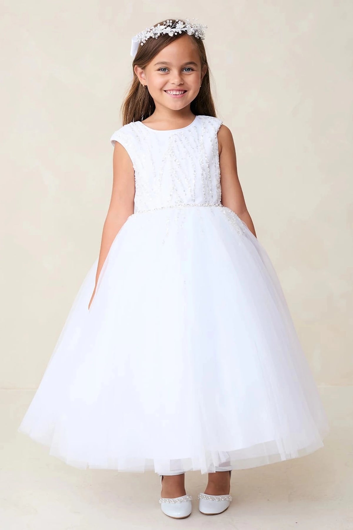 On this white flower girl dress, a full tulle skirt is visible.