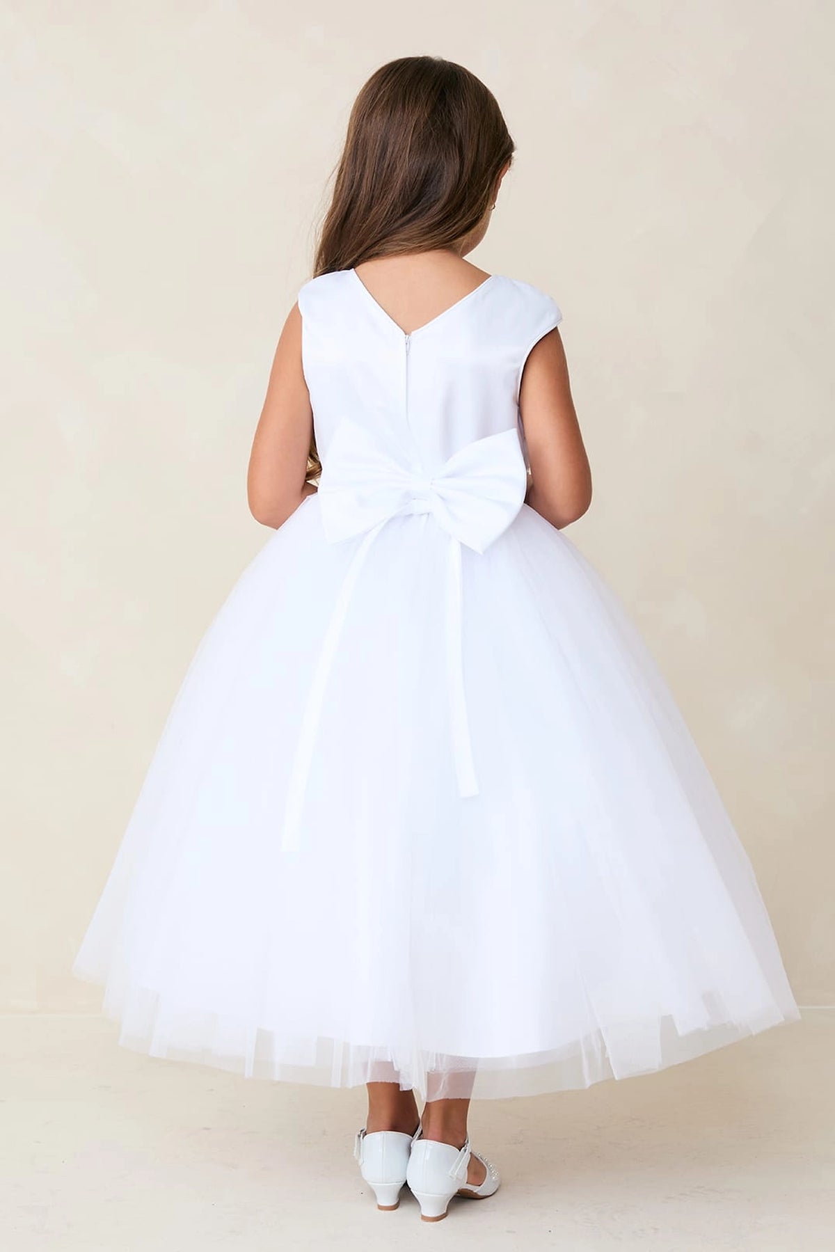 A view of a large back waist bow on the white flower girl dress.