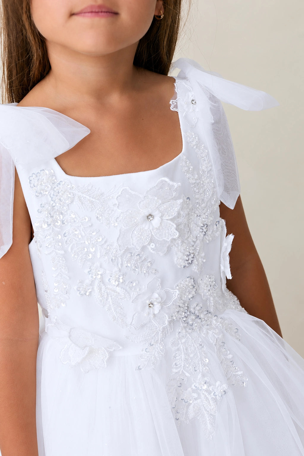 A view of a flower-trimmed square neckline on the white flower girl dress.