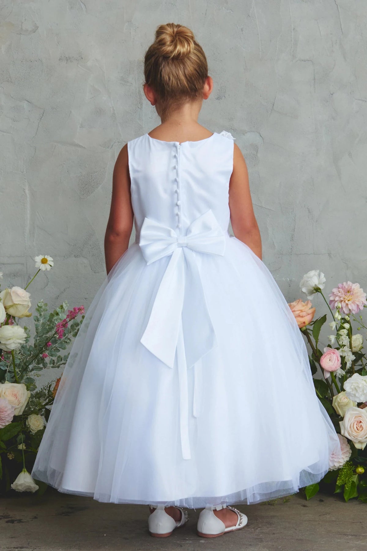 Large satin back bow on an off-white flower girl dress.
