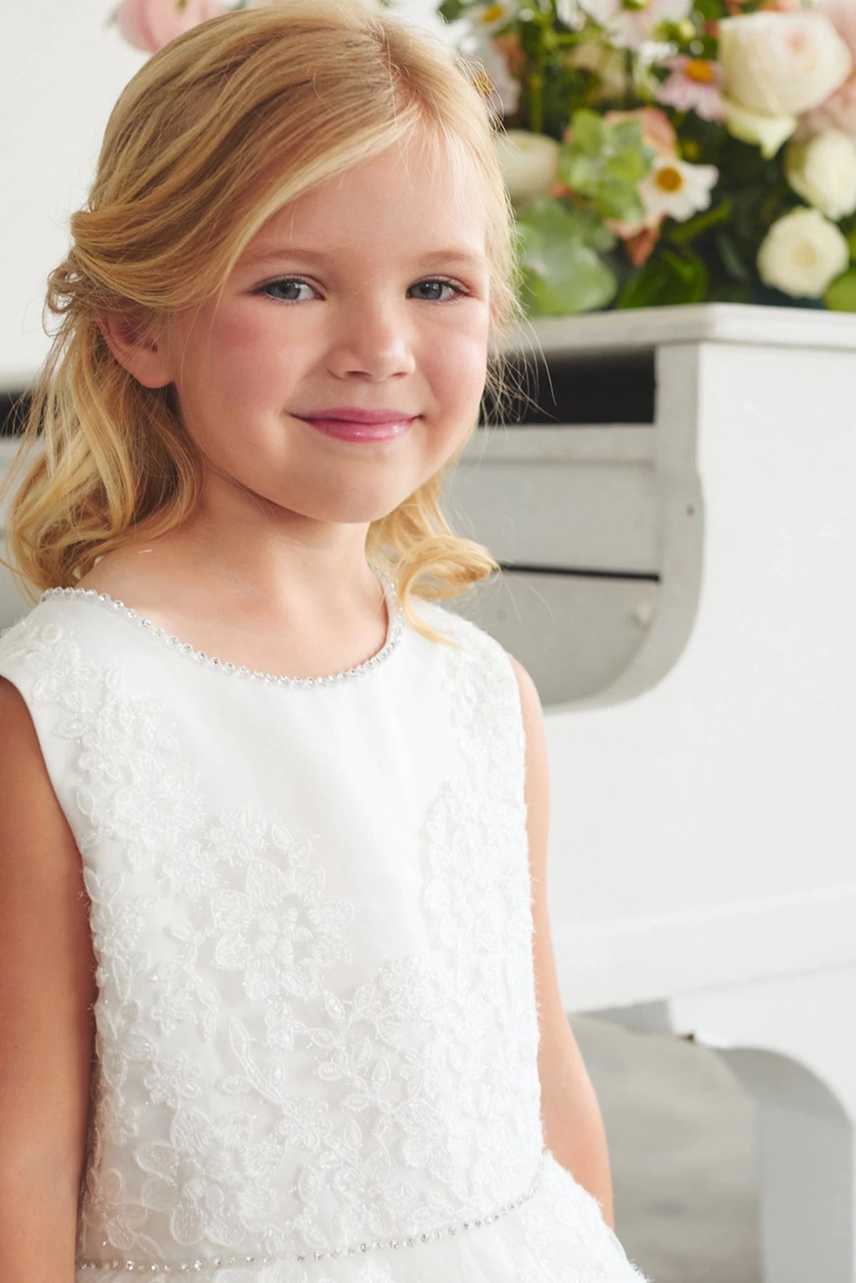 Highlighting a pearl-trimmed neckline on an off-white flower girl dress.
