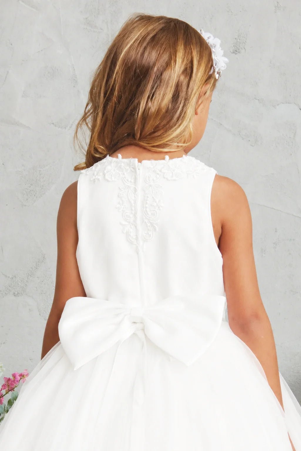 Oversized satin bow on an off-white flower girl dress.