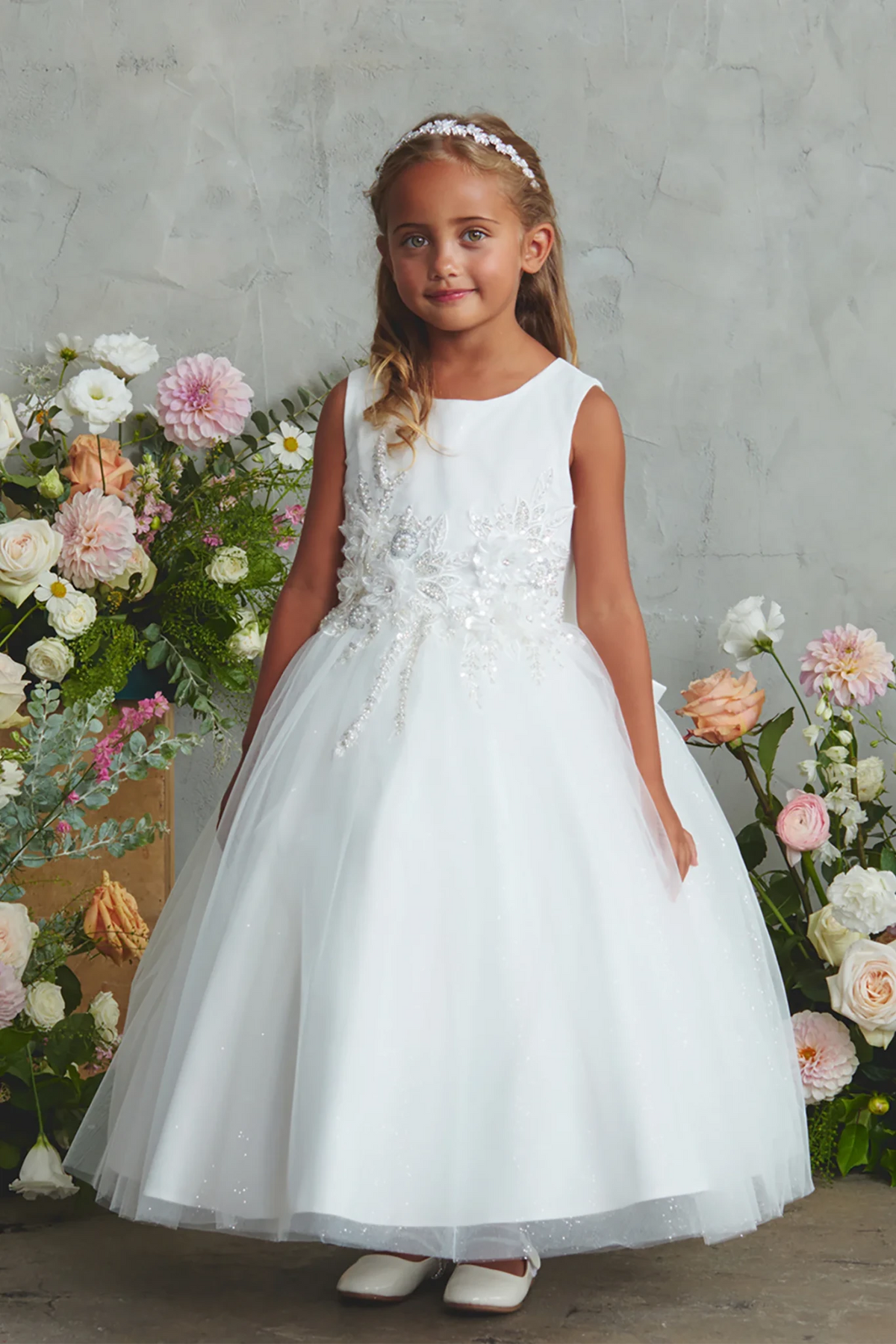 Glitter-dotted tulle overlays the off-white flower girl dress's flared skirt.