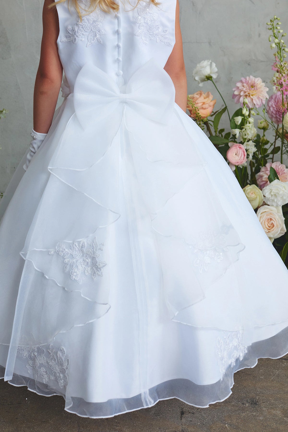 White flower girl dress detailed with a large satin back bow.