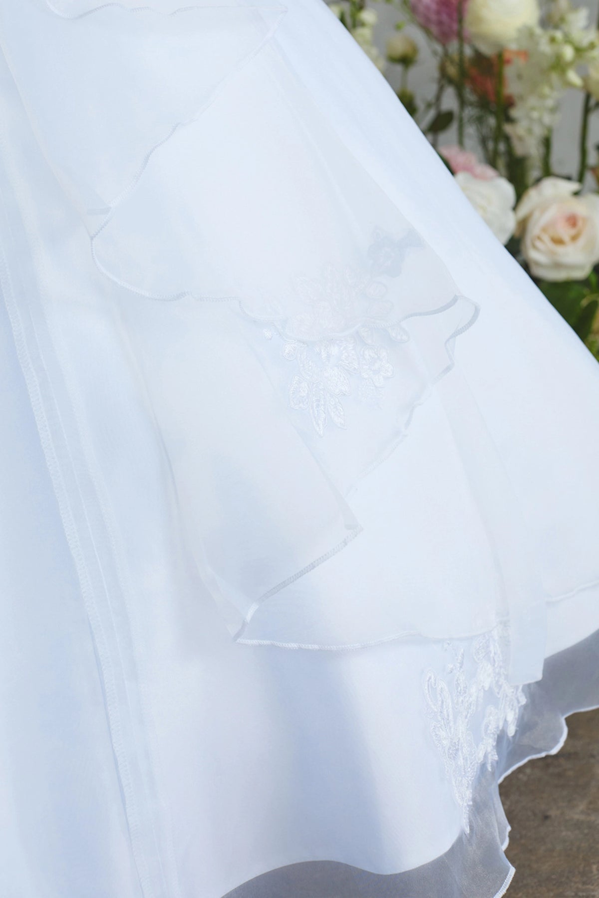 Emphasis on scalloped organza layer of the white flower girl dress.