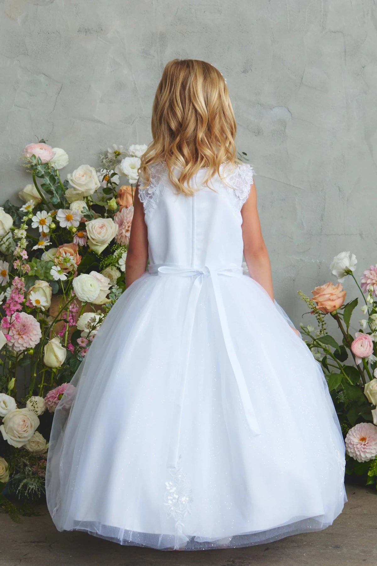Highlighting a small satin back bow on a white flower girl dress.