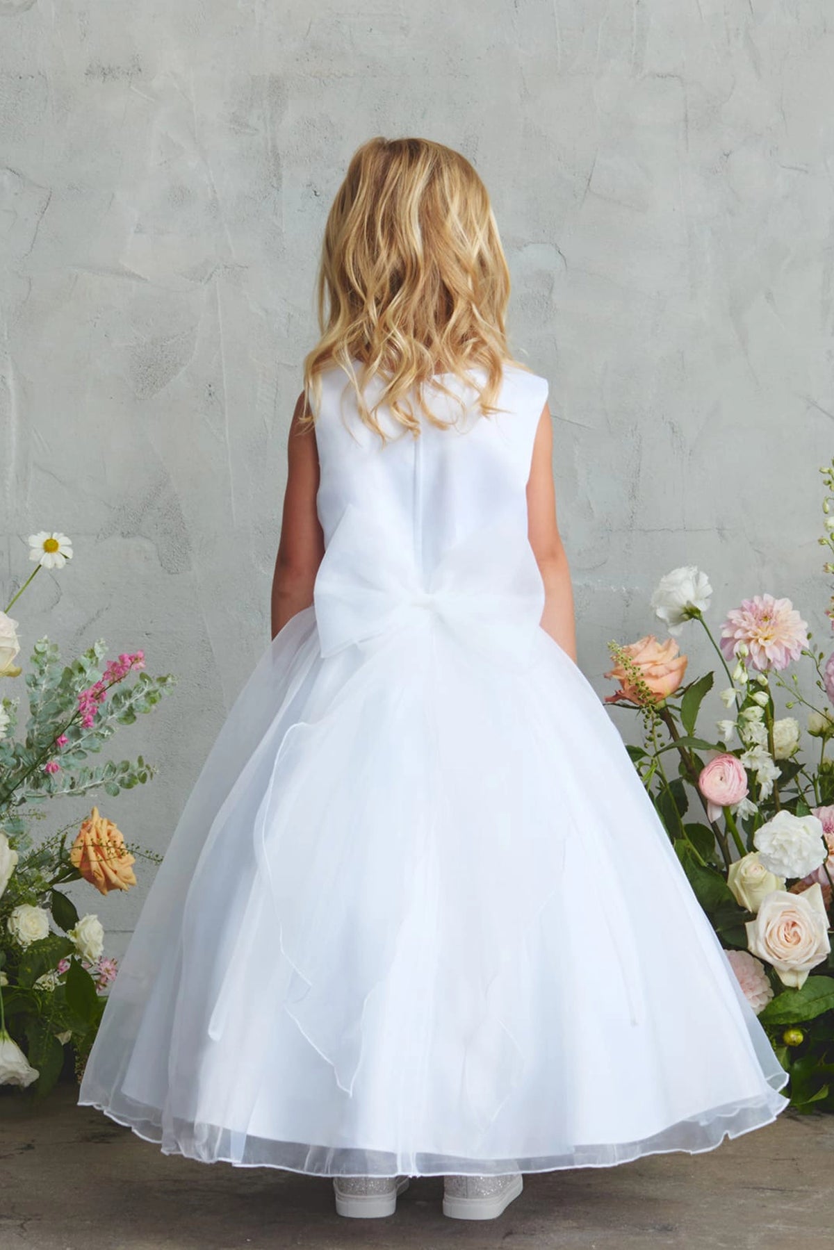White flower girl dress featuring a small tied back bow.