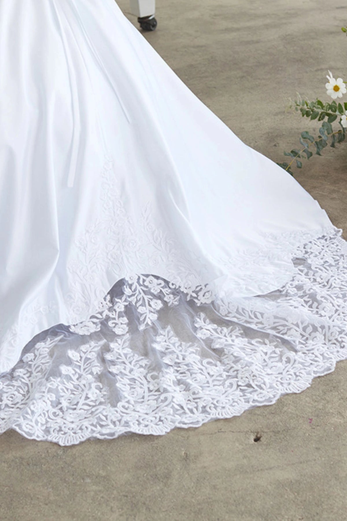 Highlighting a scalloped lace train edge on a white flower girl dress.