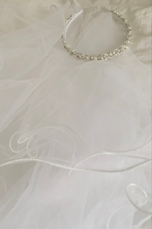 crystal and pearl headband tiara with 2-tier veil on a white fabric background