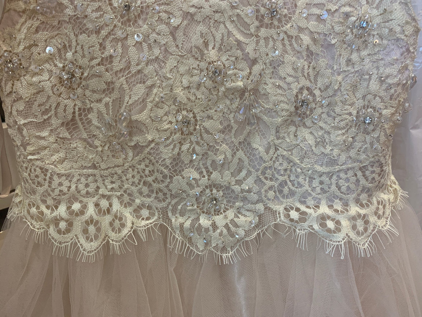 Close-up of a lace communion dress with intricate patterns and embellishments.
