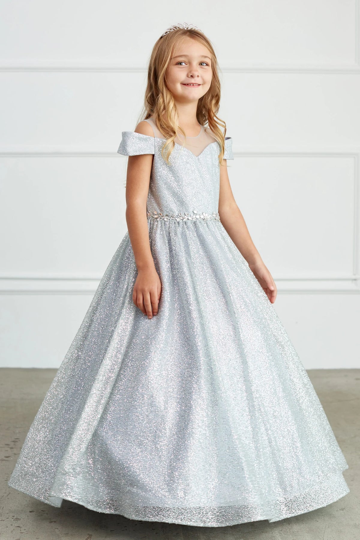 Silver kids pageant dress featuring a rhinestone waist and glitter skirt.