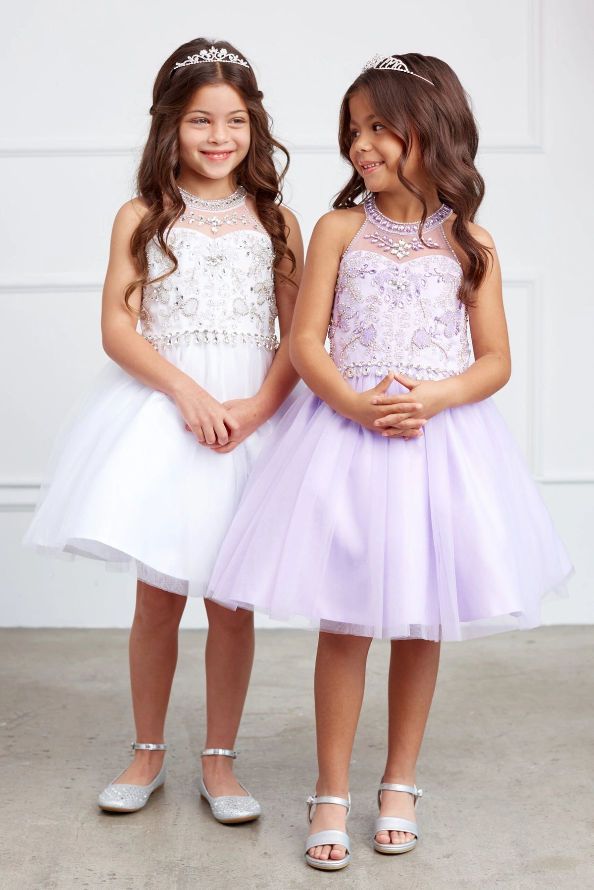 Side-by-side White and Lilac kids pageant dresses have beaded waist details and soft mesh skirts.