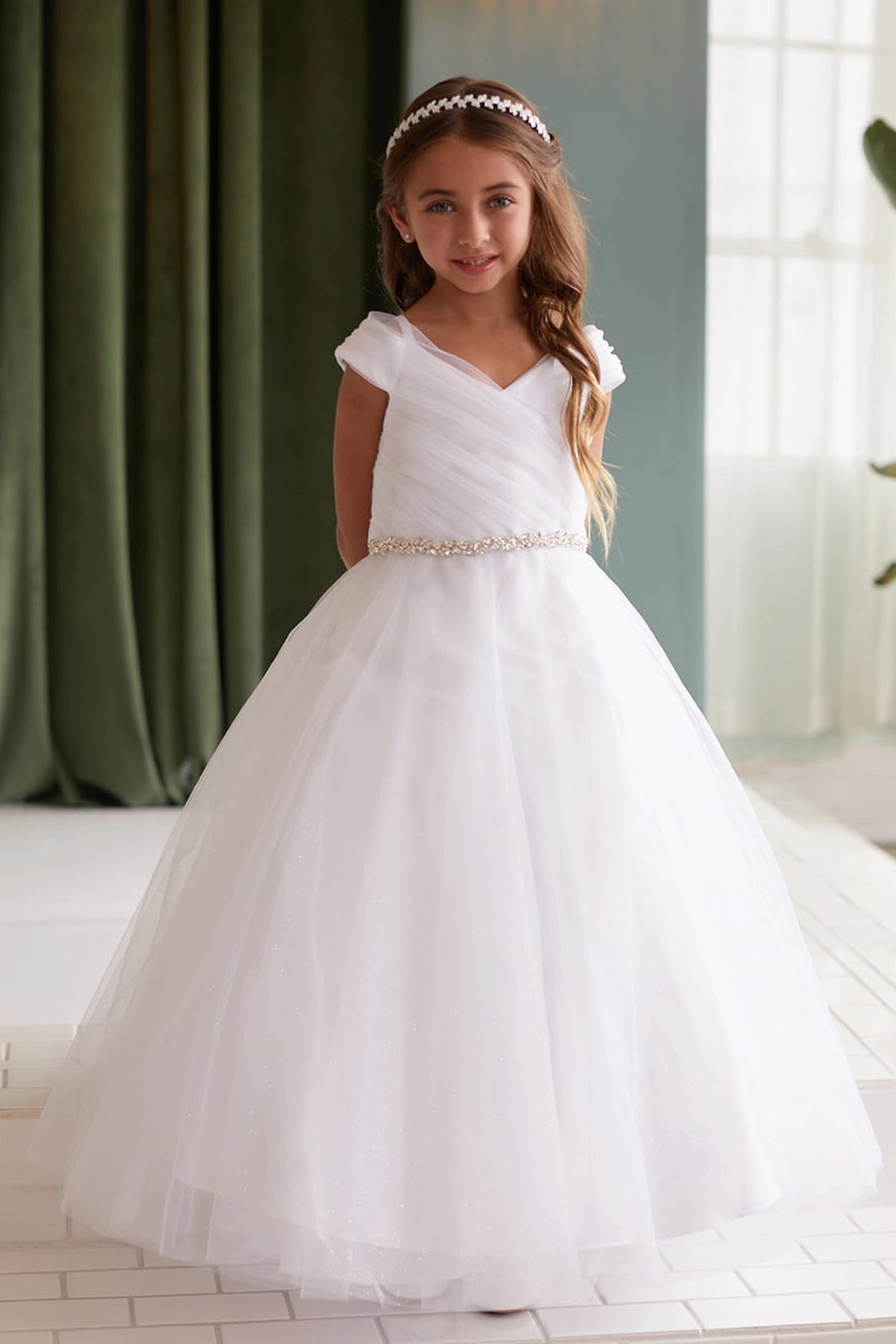 White kids pageant dress featuring an asymmetrically pleated neckline.