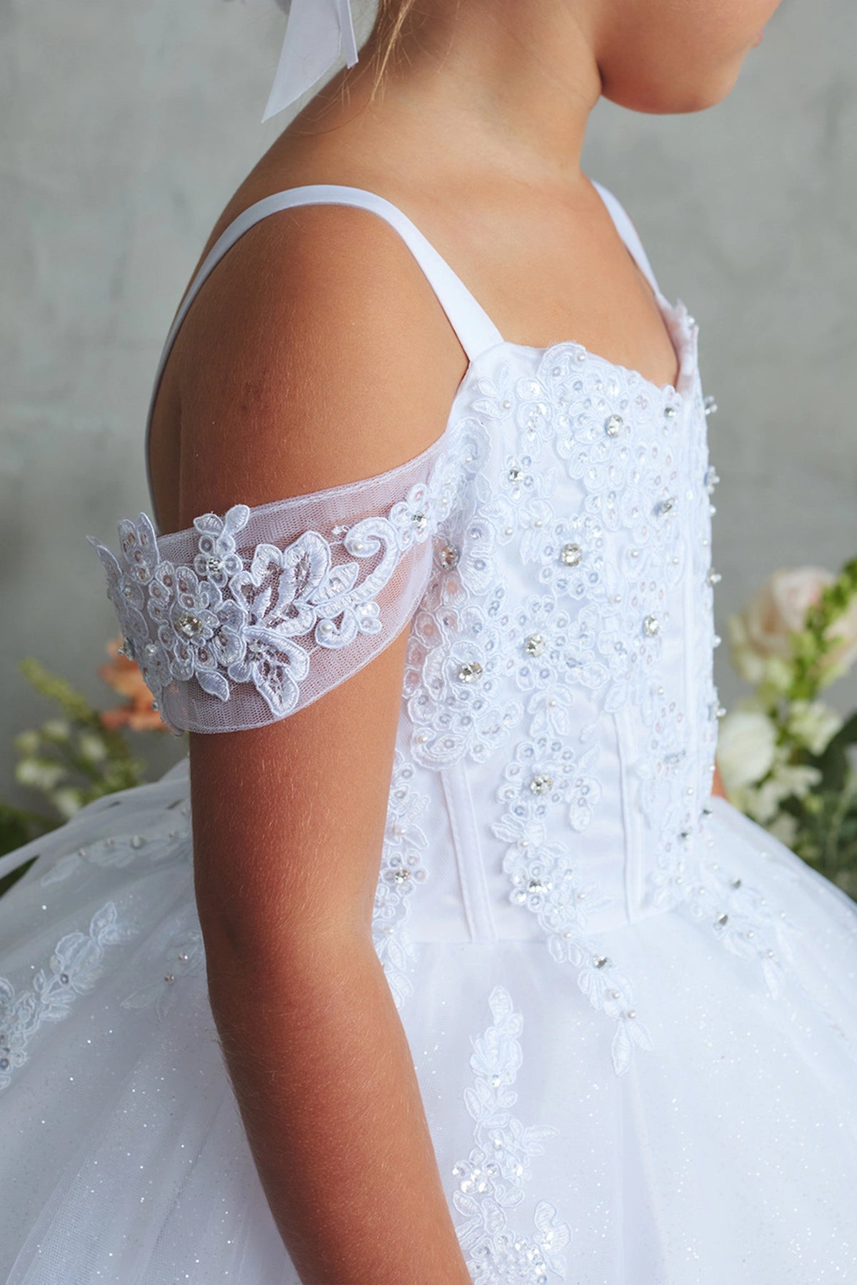 On the White kids pageant dress, the detailing includes lace on a draped shoulder strap.