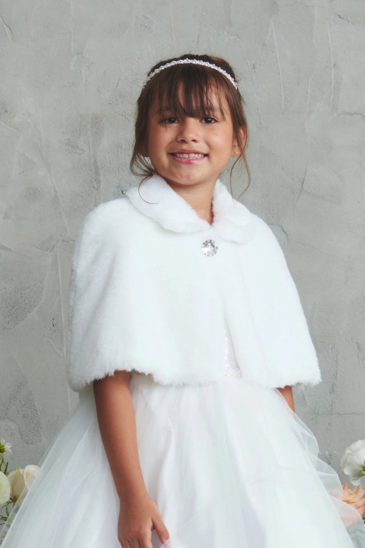 Rhinestone accent at the collar of the White faux fur cape.