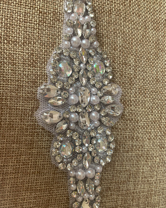 Decorative silver belt with pearls and crystals on a textured brown background