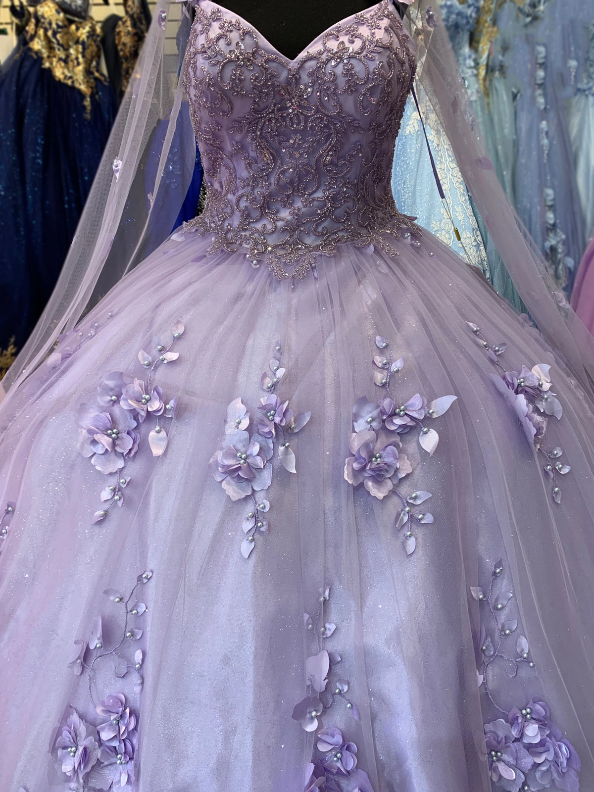 Bodice close-up highlights Lilac quinceanera dress with floral appliques, bead detailing, and glitter tulle fabric.