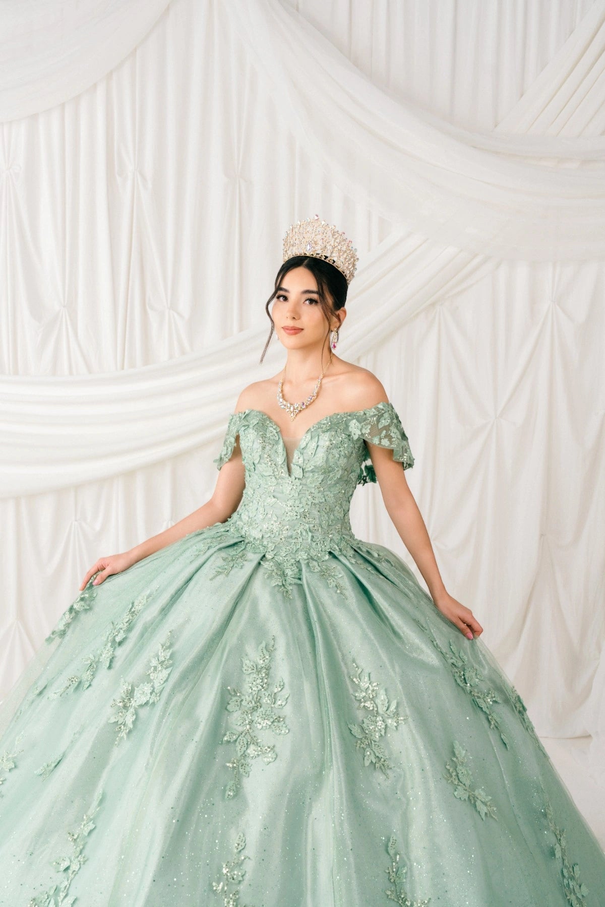 Shown in a full-skirt front view, the Sage quinceañera dress has off-shoulder floral lace bodice and glitter ball skirt.