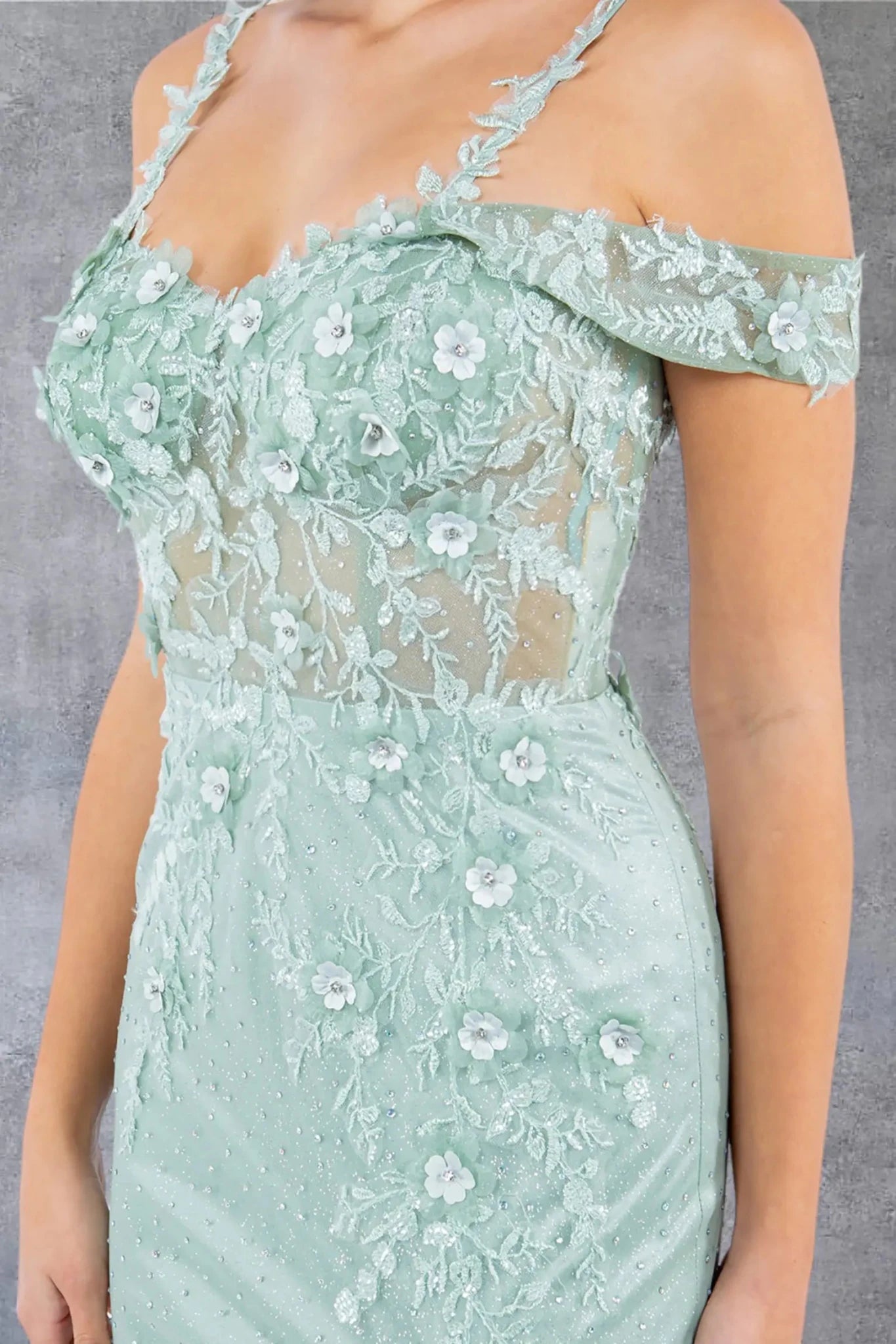 A close-up view of a woman wearing a sage floral appliqué bodice with rhinestone detail.