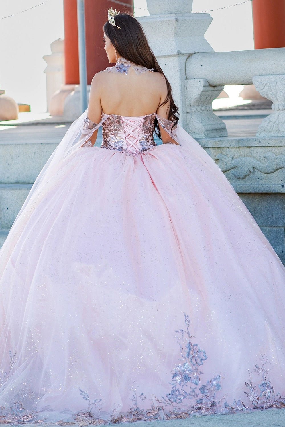 Presented in a back view, the Blush quinceañera dress has lace-up closure and floral lace along the skirt hem.