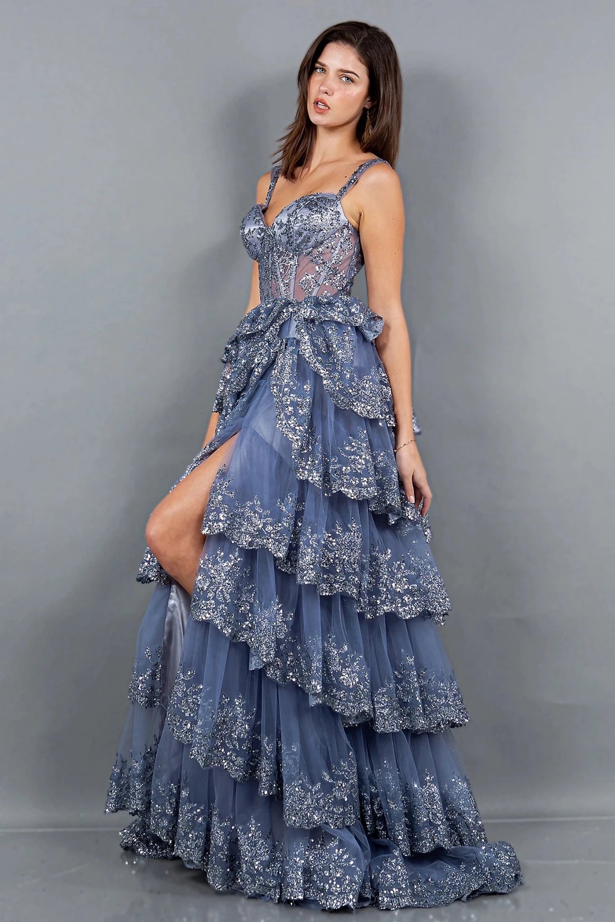 Textured details appear across smoky blue evening dress showcasing ruffled tiered skirt with high side slit.