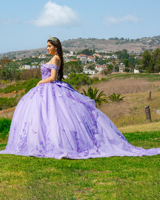 Woman in a lilac gown standing outdoors with a scenic background